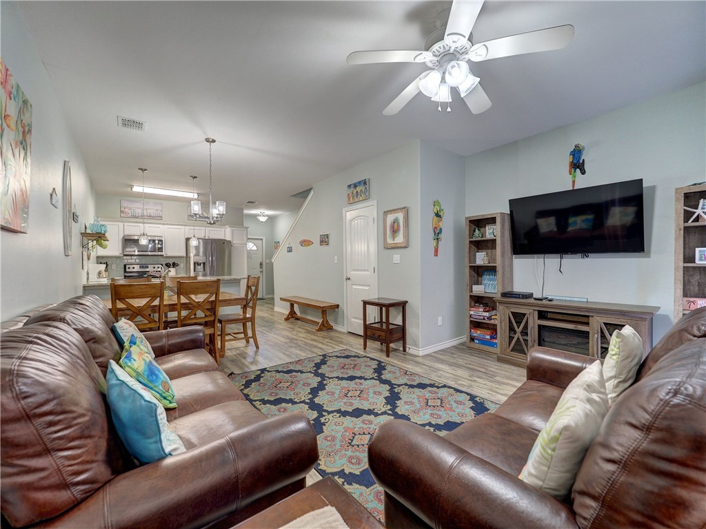 Furnished living room with leather sofas, patterned rug, and open kitchen.