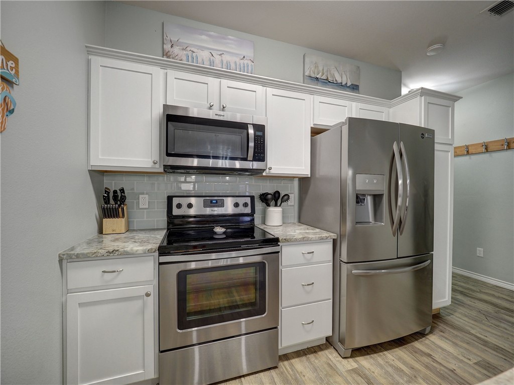 Kitchen with white cabinets, stainless steel appliances, and a gray tile backsplash.