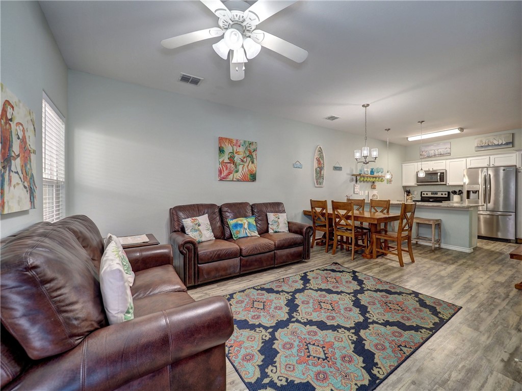 Open-plan living and dining area with brown leather sofas, a patterned rug, and a wood dining table.