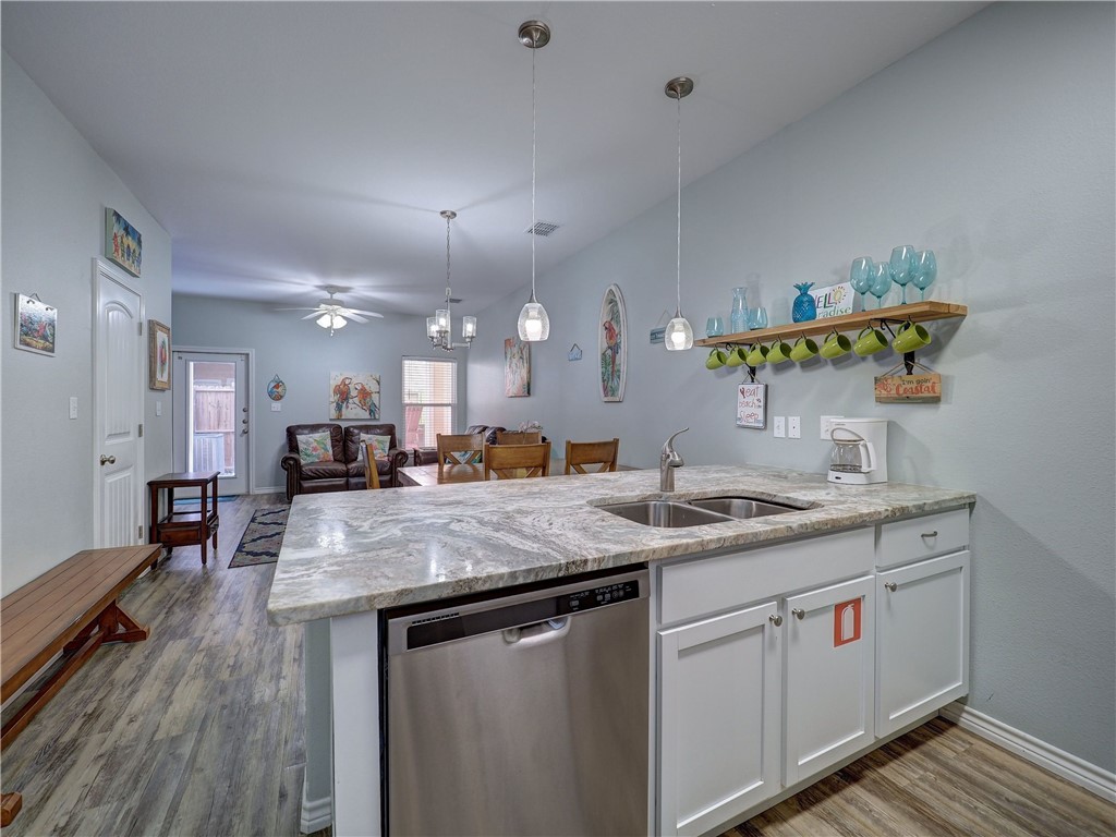 Open-plan kitchen with a large stone island, double sink, and dining and living areas beyond.