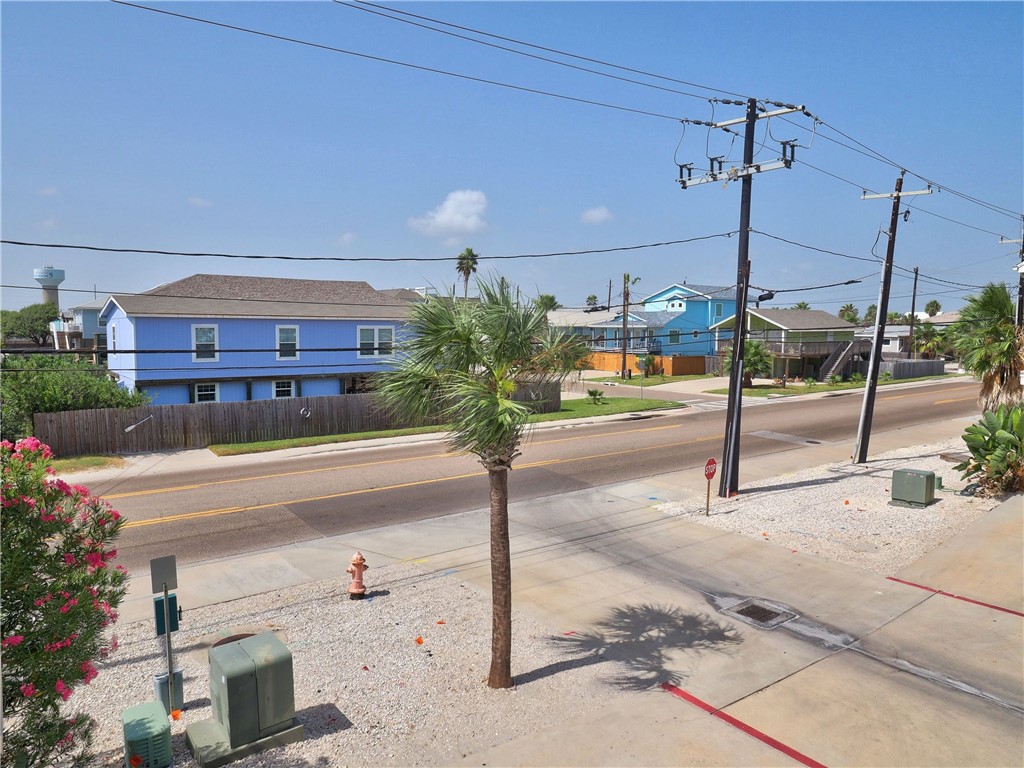 Residential street with colorful coastal homes, palm trees, and overhead utility lines.