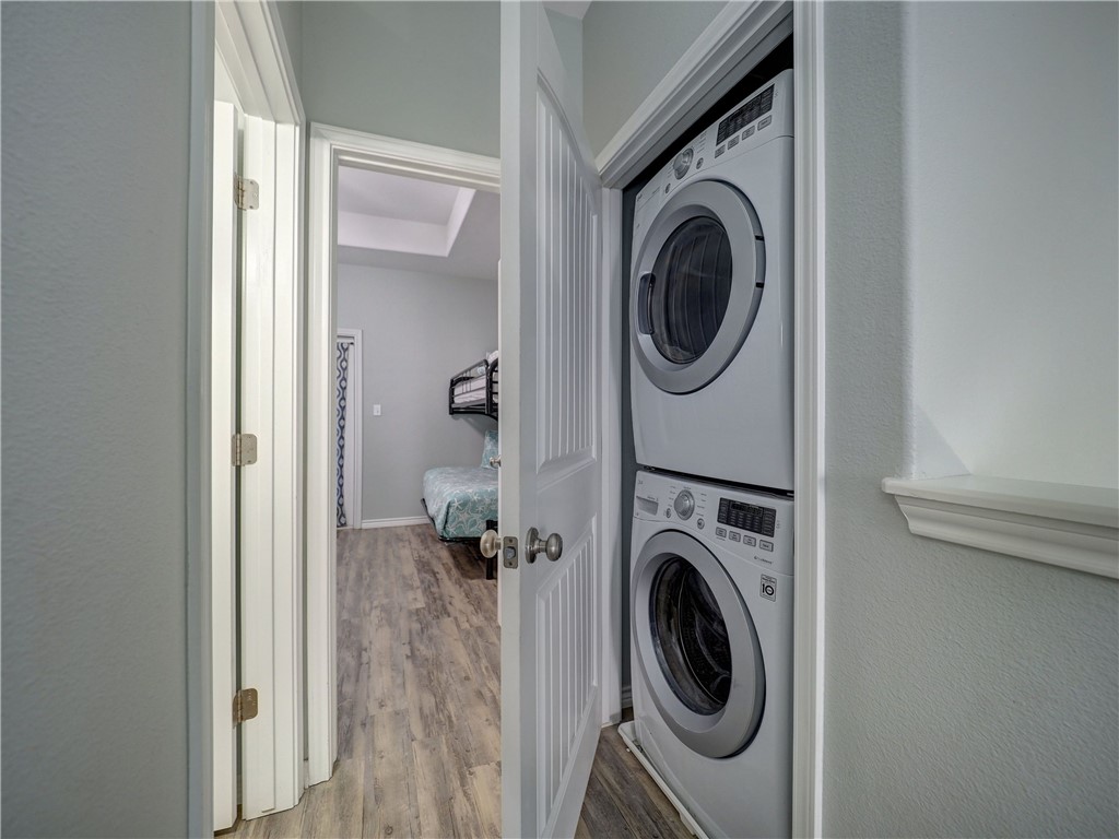 Stacked washer and dryer beside a bedroom with a bunk bed.