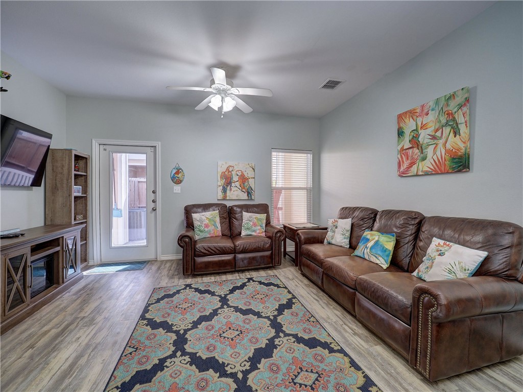 Living room with brown leather sofas, a colorful patterned rug, and tropical wall art.