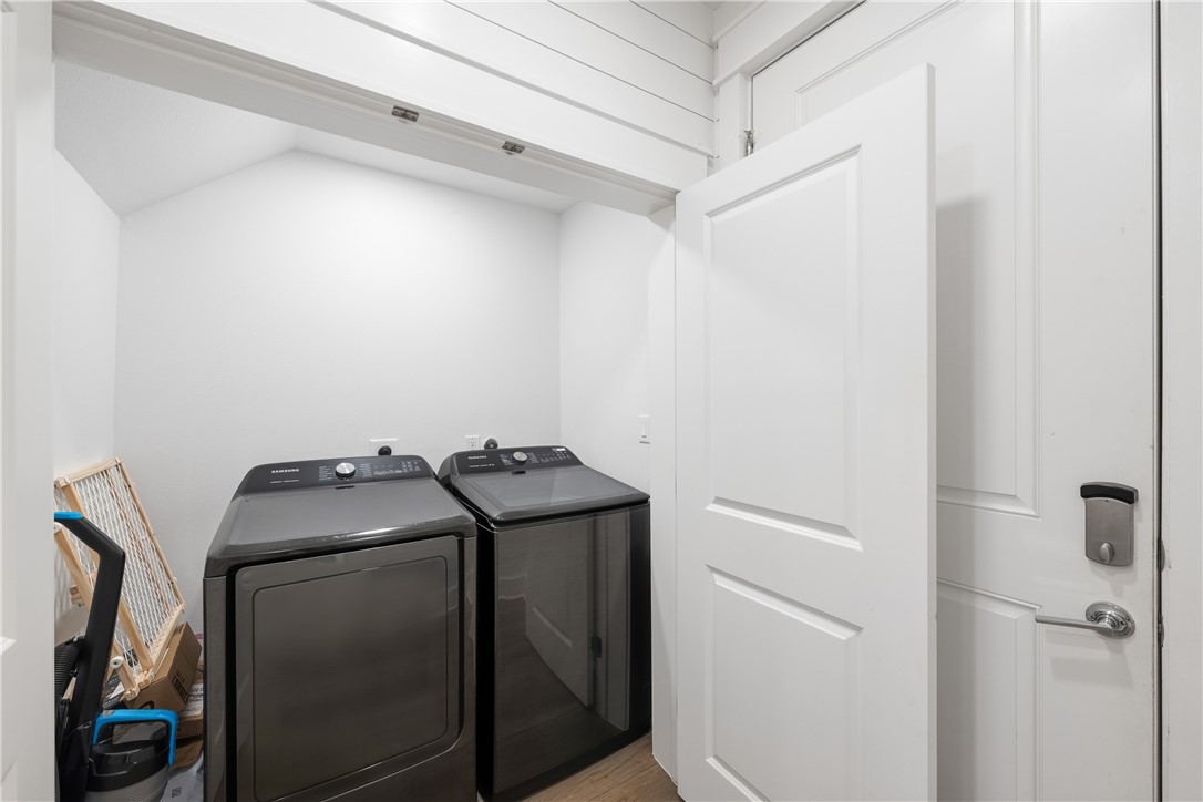 Laundry room with dark washer and dryer beside an open white door.