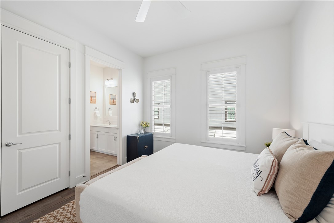 Bright bedroom with a white bed, neutral pillows, and two shuttered windows.