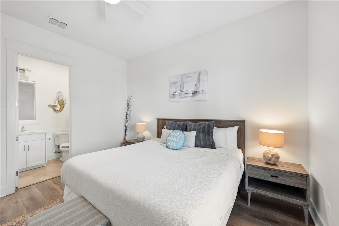 Bedroom with a king bed, coastal decor, and an open doorway to the ensuite bathroom.