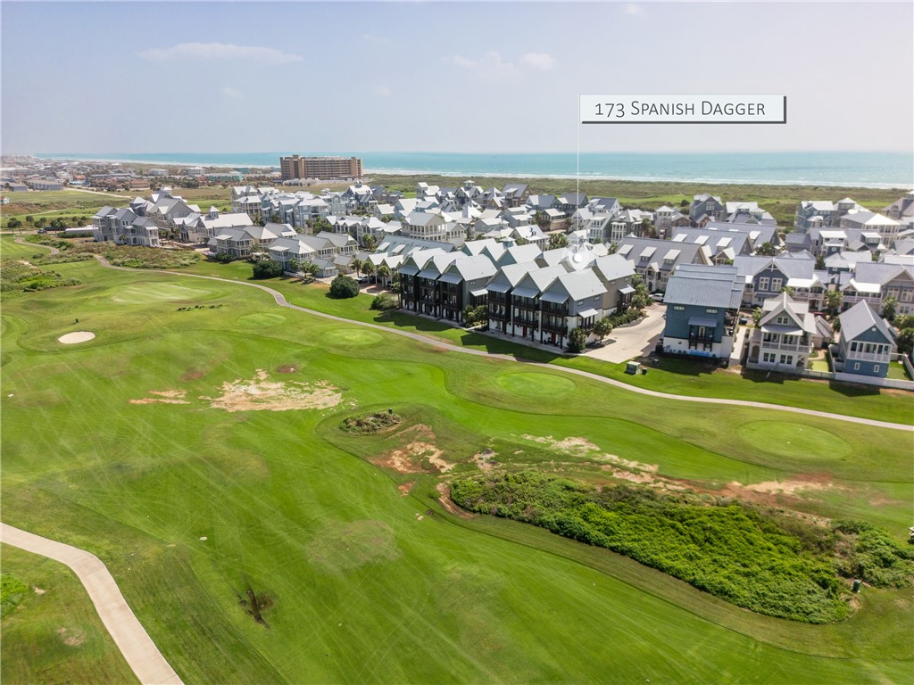 Aerial view of 173 Spanish Dagger beside a golf course, with the ocean beyond the coastal homes.