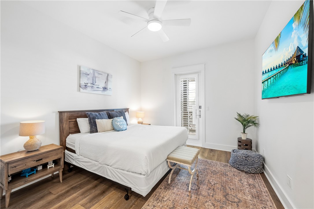 Bedroom with a white bed, dark wood headboard, patterned rug, and glass-paneled door.