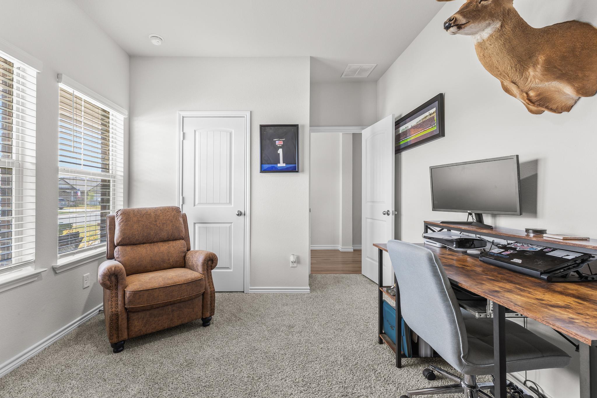 Home office with a brown recliner, wood desk, computer, and mounted deer head.