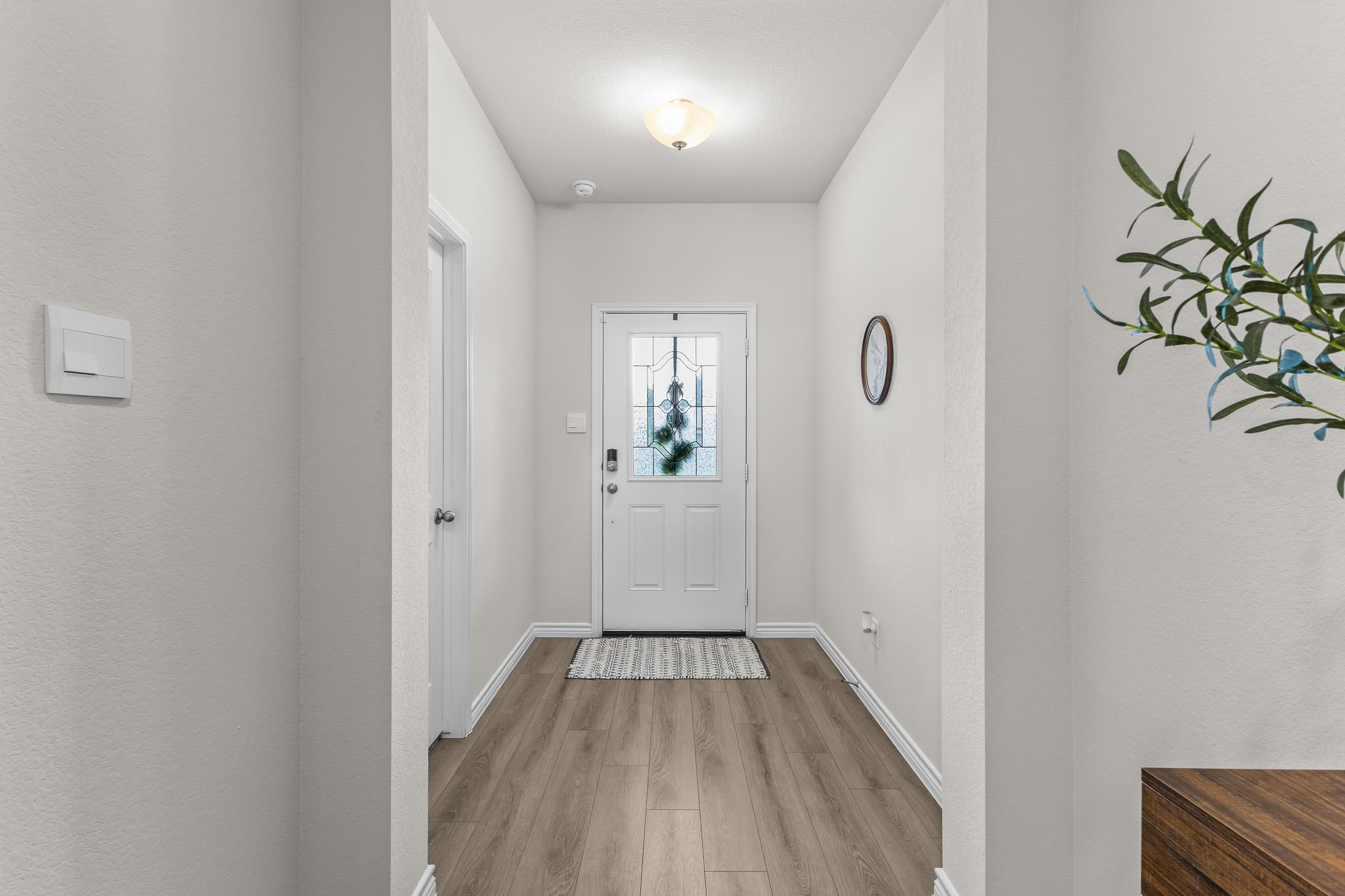 Entry foyer with a blue stained-glass front door, wood-look flooring, and a patterned rug.