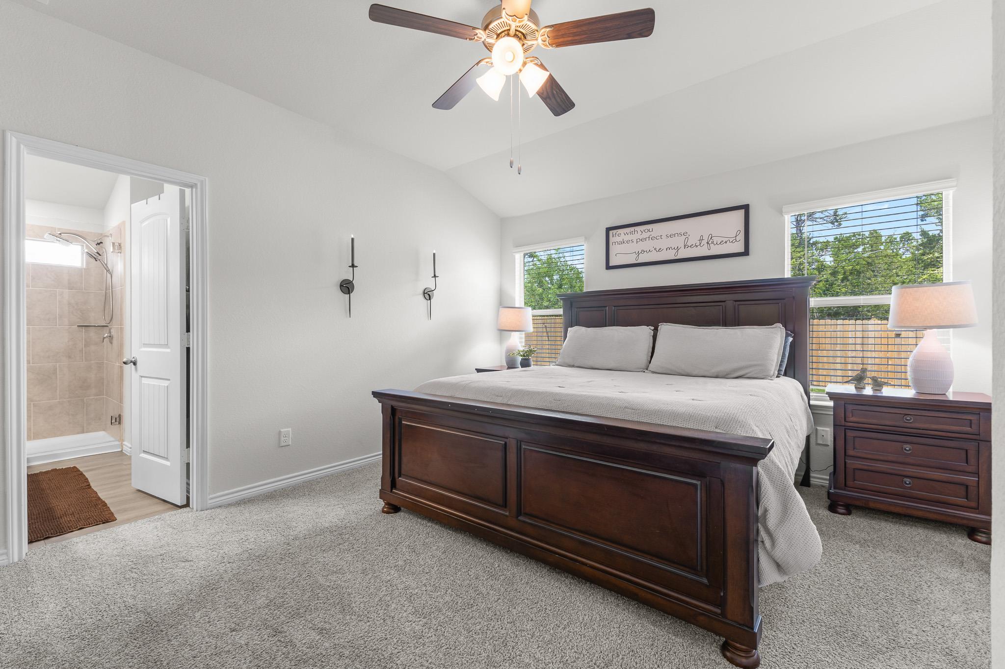 Furnished bedroom with a dark wood bed, ceiling fan, and adjoining tiled shower bathroom.
