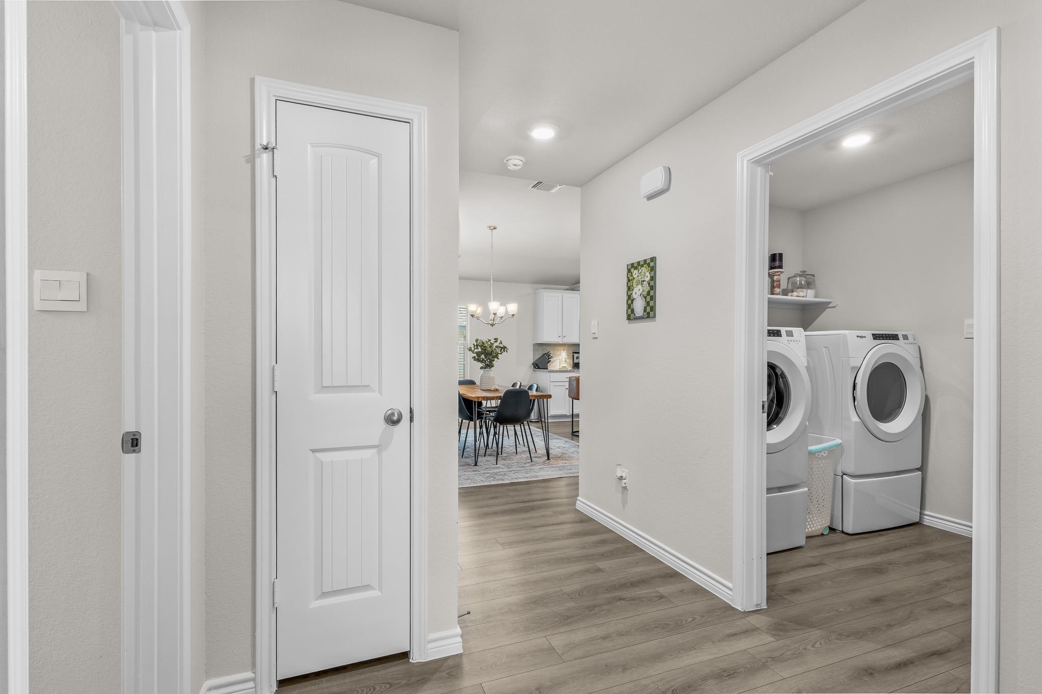 Hallway leading to a dining area, with a laundry room and white washer and dryer on the right.
