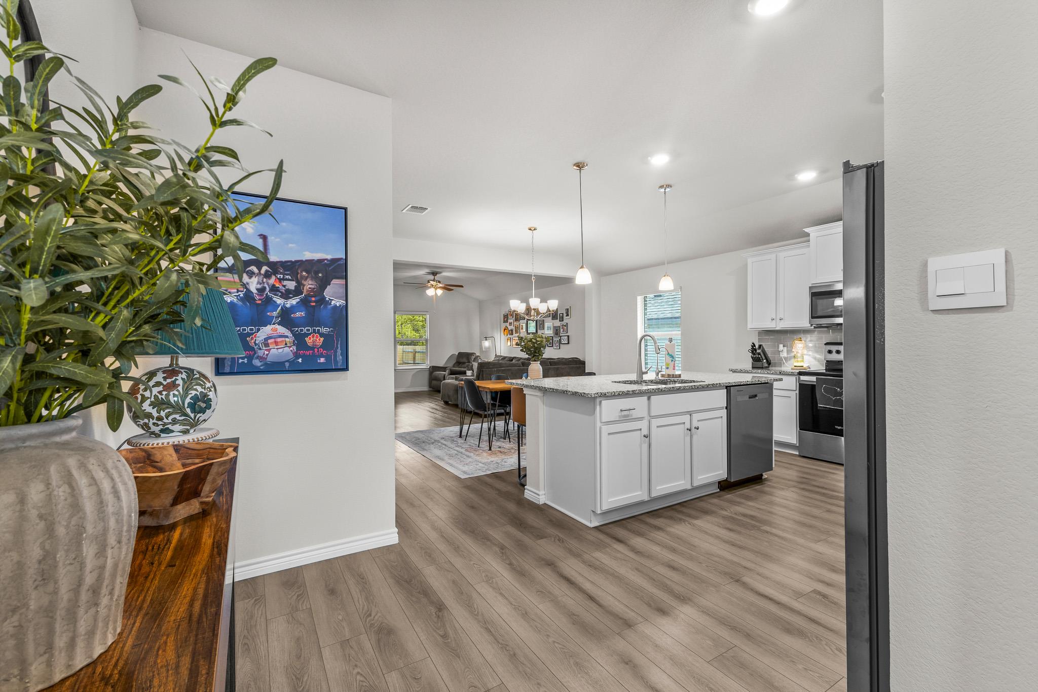Open-plan kitchen with a large white island, granite countertop, and dining and living areas beyond.