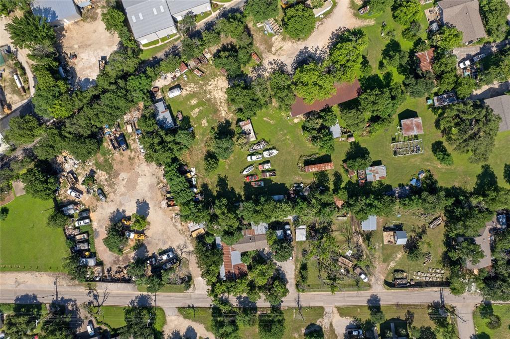Aerial view of wooded land with dirt clearings, small outbuildings, and boats.