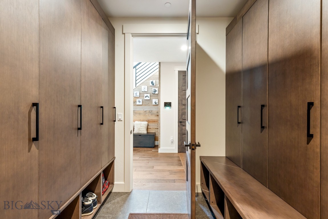 Mudroom with tall wood cabinets, built-in benches, and shoe cubbies on both sides.