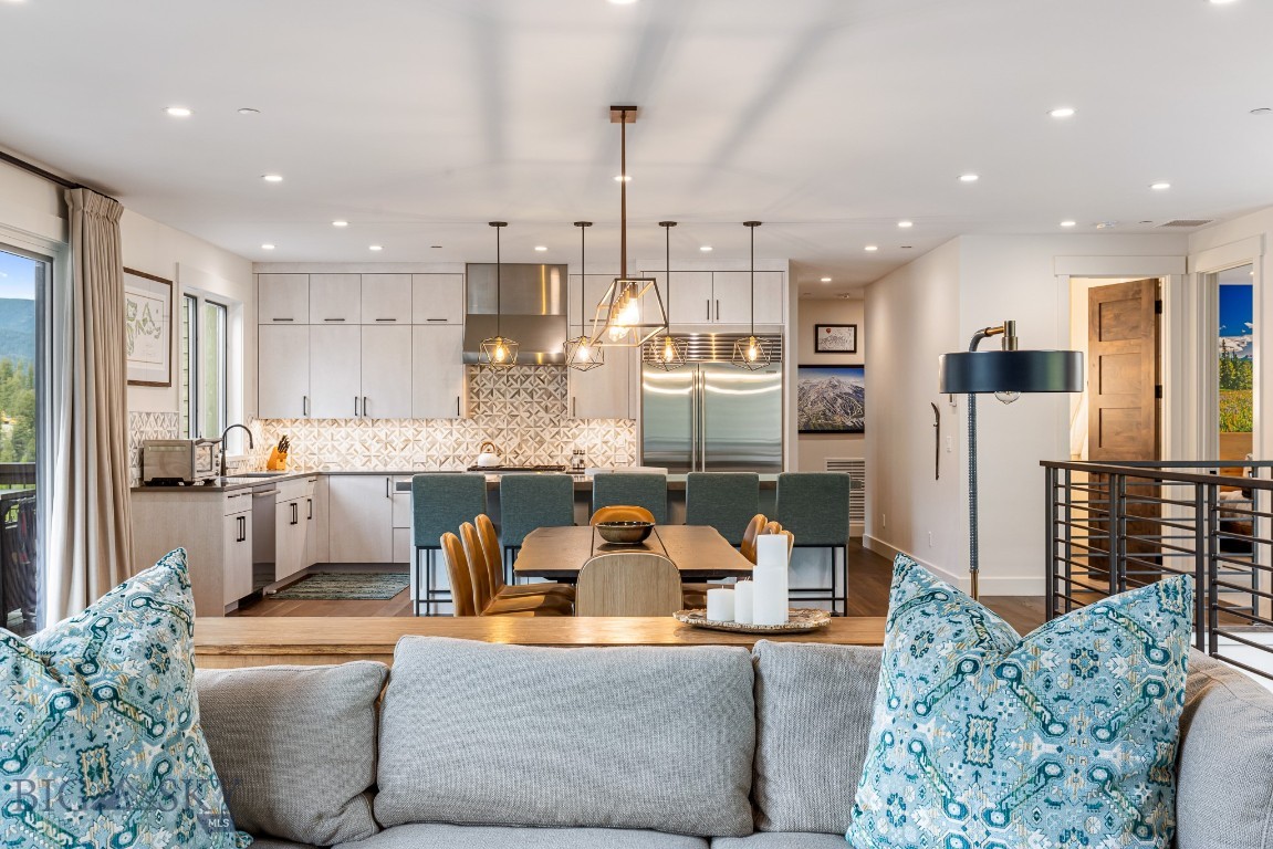 Open-plan kitchen and dining area with white cabinetry, geometric backsplash, and mountain views.