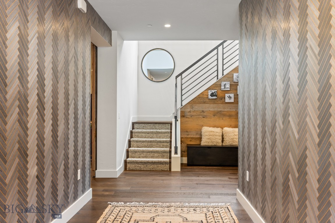 Entry hall with patterned walls, carpeted stairs, metal railing, and a wood-paneled seating nook.