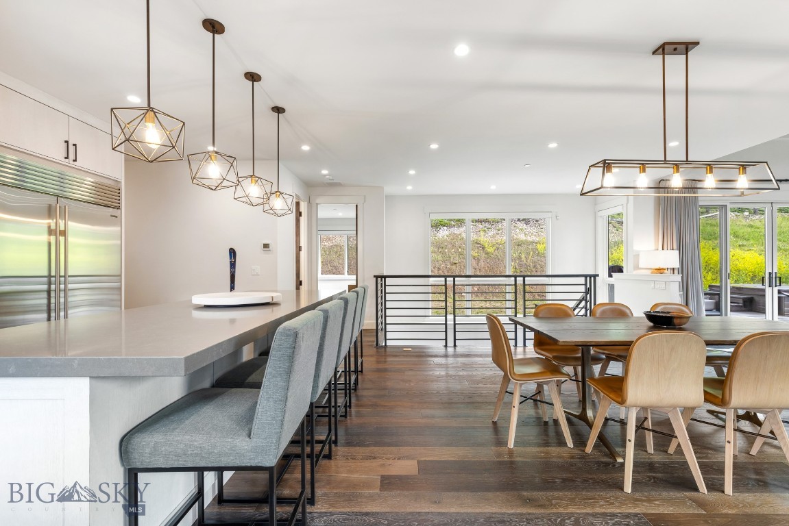 Open-plan kitchen and dining area with a stone island, gray stools, and large windows.