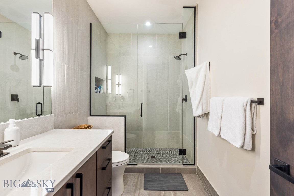 Bathroom with a glass-enclosed walk-in shower and white vanity.