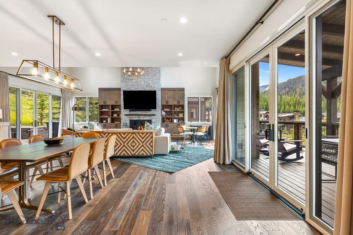 Open living and dining room with a stone fireplace and sliding doors to a mountain-view deck.