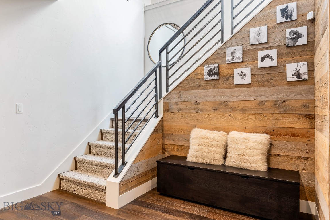 Entryway staircase beside a wood-plank wall, with a dark bench and wildlife prints.