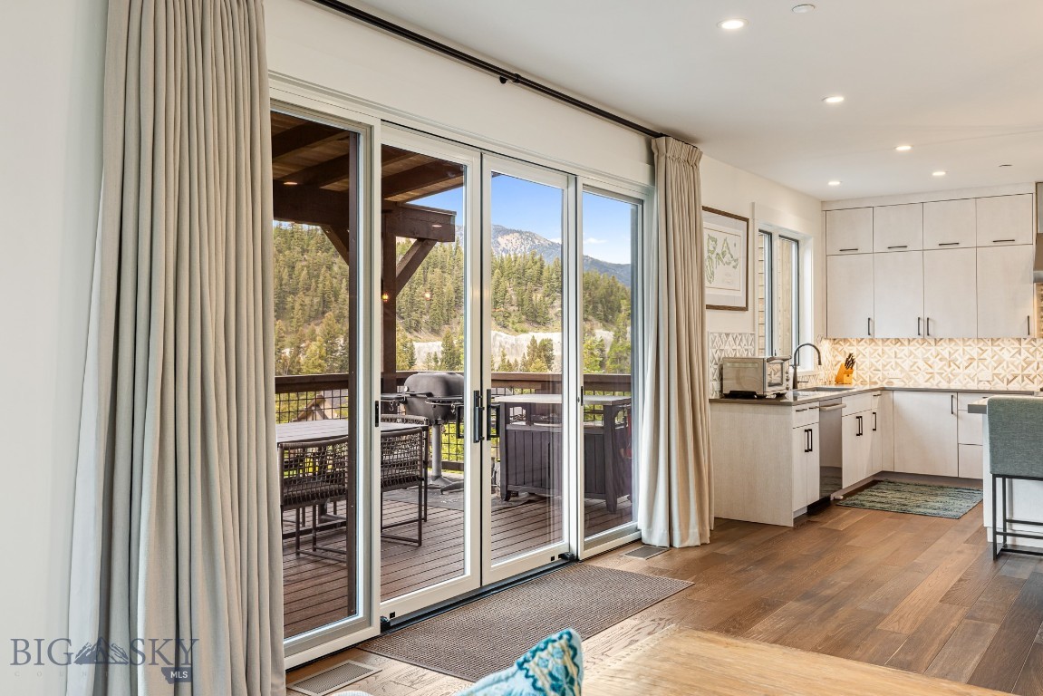 Bright kitchen with sliding glass doors opening to a deck with outdoor seating and mountain views.