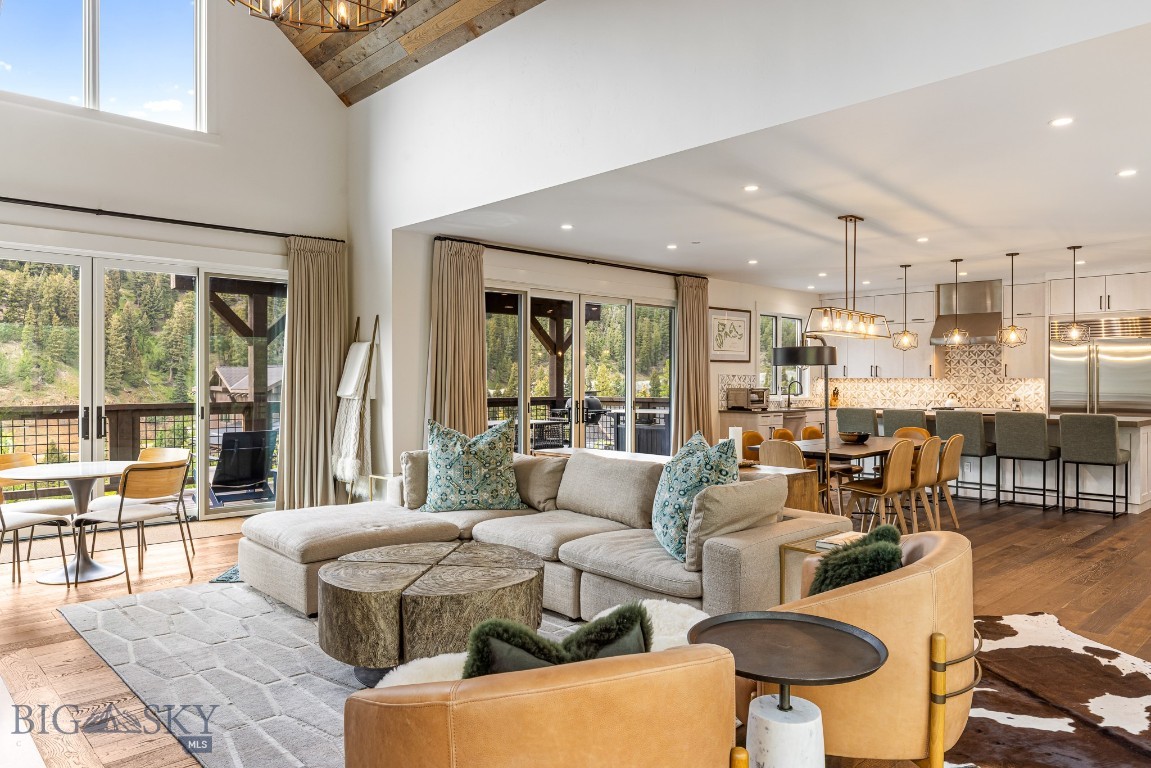 Open-plan great room with a vaulted ceiling, large windows, and a modern kitchen.