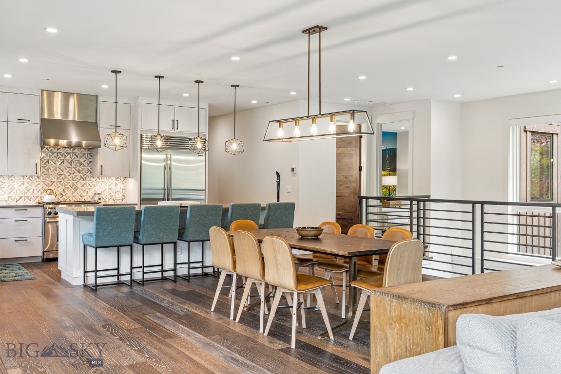 Open-plan kitchen and dining area with a large island, blue stools, and a wood dining table.