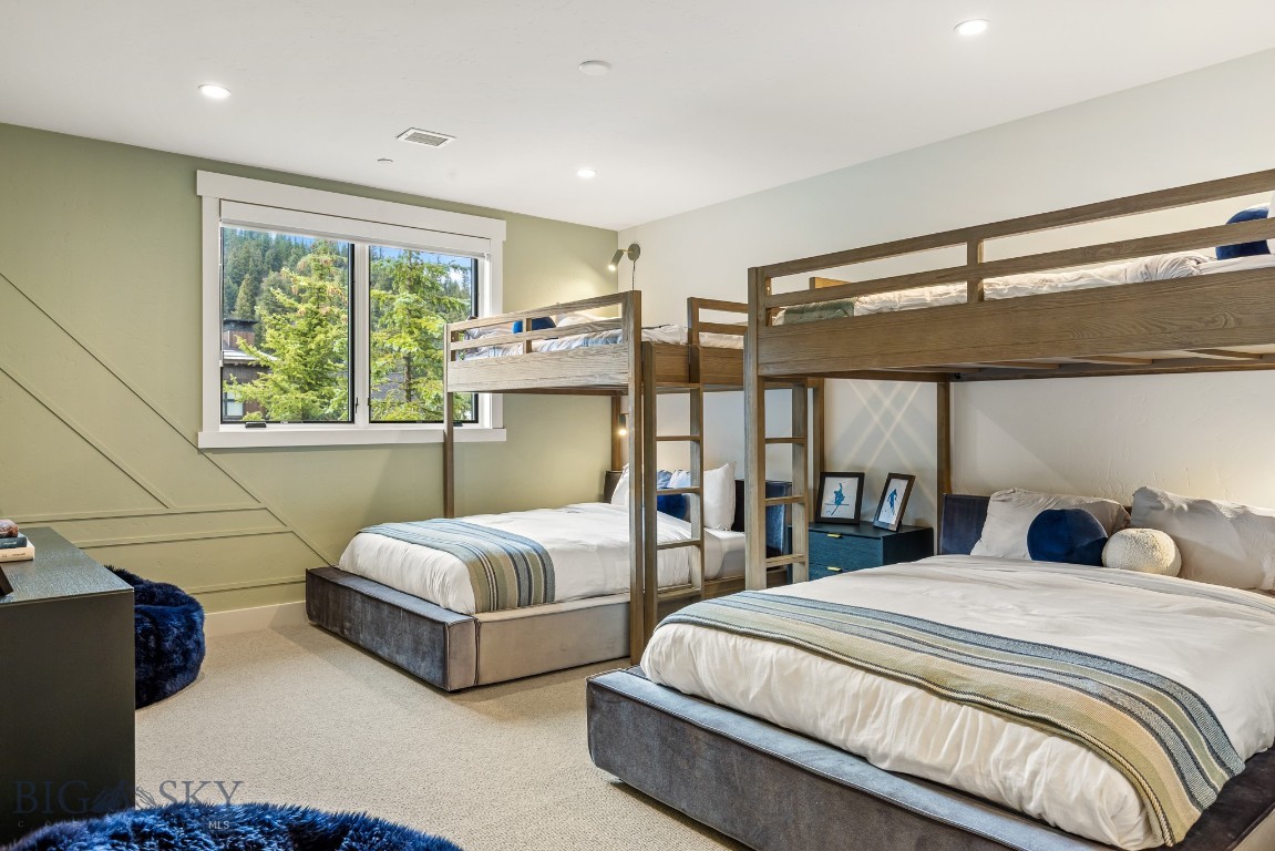 Bedroom with wooden bunk beds, two lower beds, striped bedding, and a window overlooking trees.