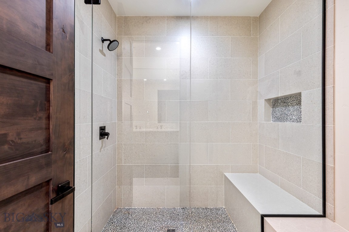 Walk-in shower with beige tile, a built-in bench, and mosaic tile accents.