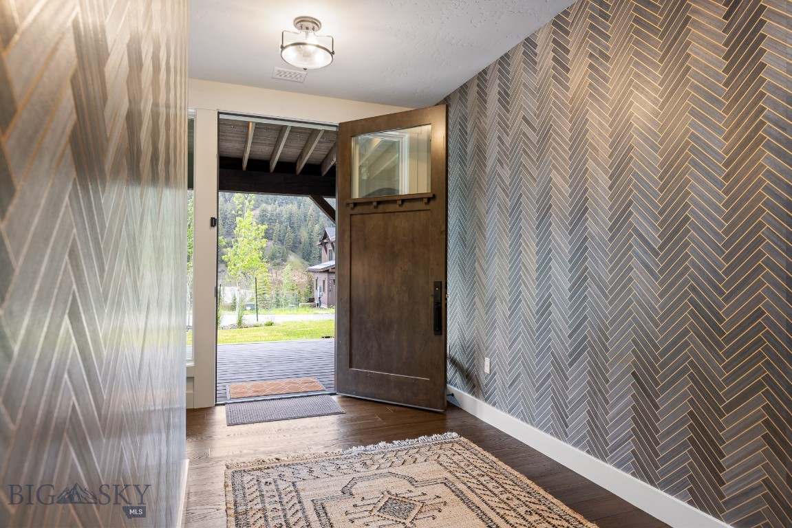 Entry foyer with gray herringbone walls and an open wooden door to the deck.