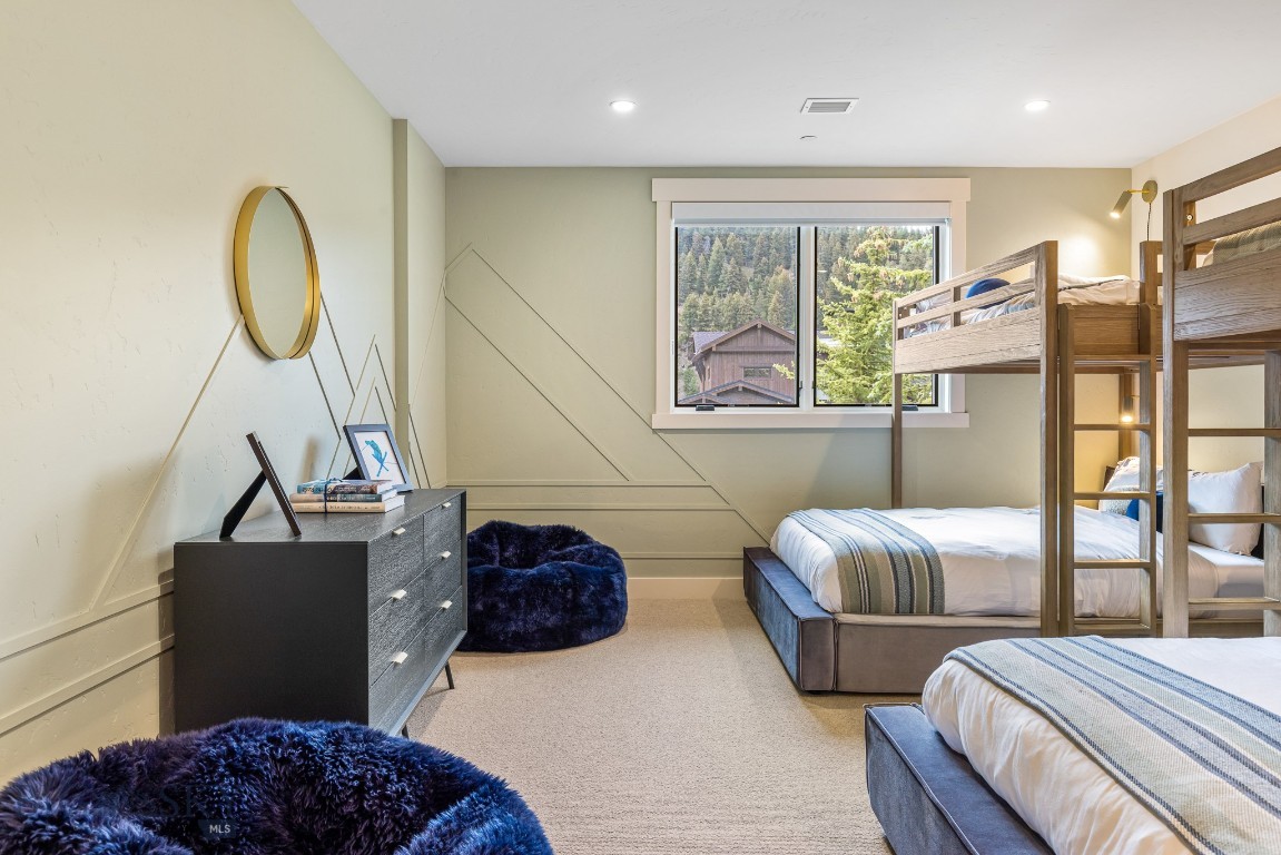 Furnished bedroom with wooden bunk beds and a window overlooking trees.