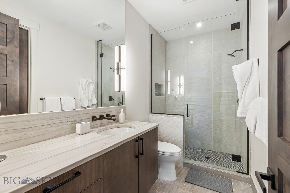 Modern bathroom with a veined stone vanity and glass-enclosed tiled shower.