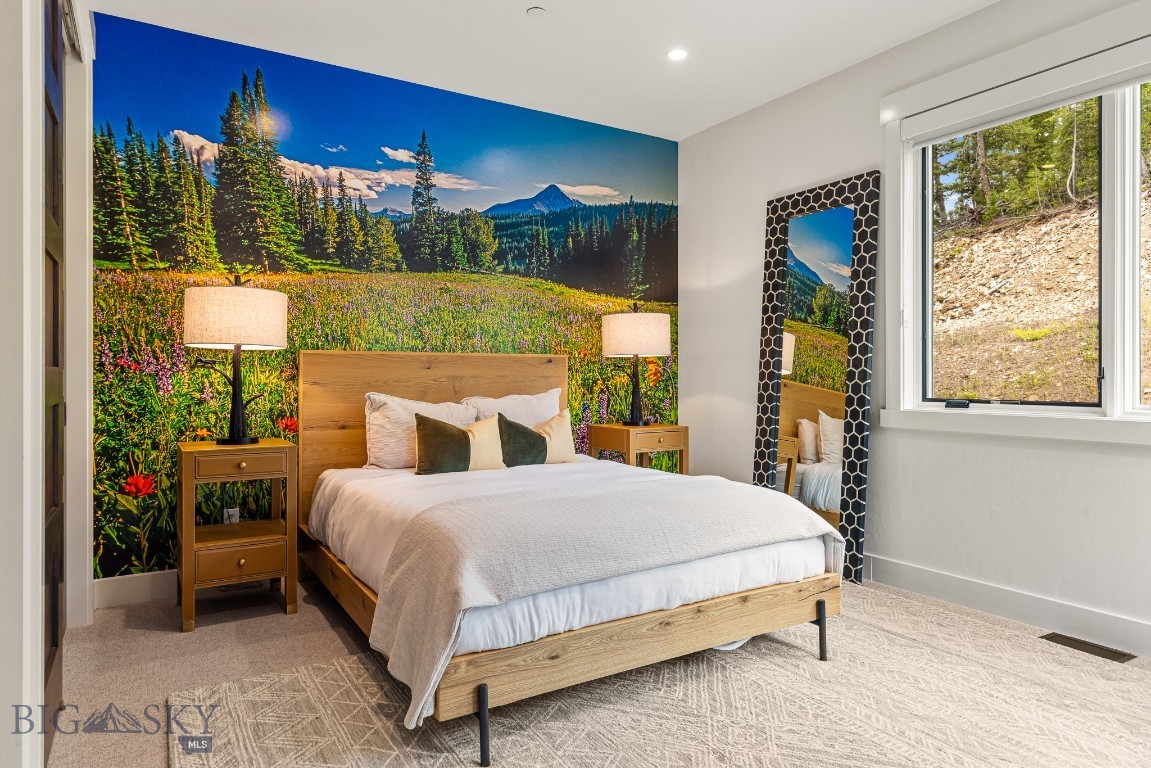 Furnished bedroom with wood bed and a vivid mountain-meadow mural behind it.