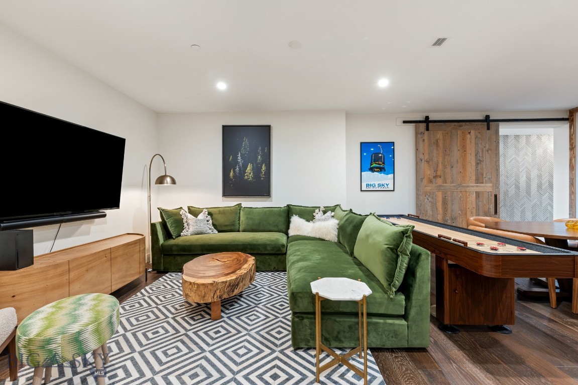 Furnished family room with a green sectional, geometric rug, and pool table.