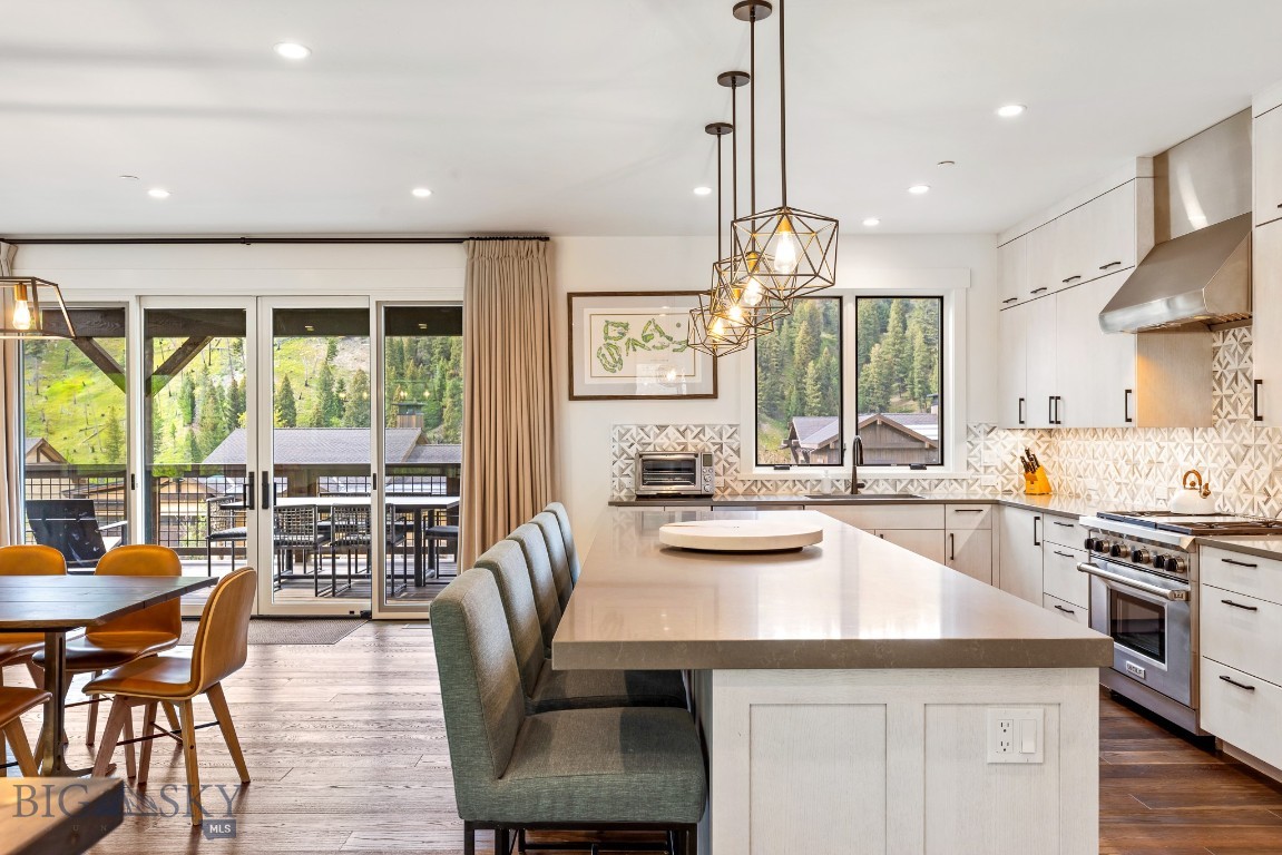 Open kitchen with a large stone island, geometric tile backsplash, and sliding doors to a deck.