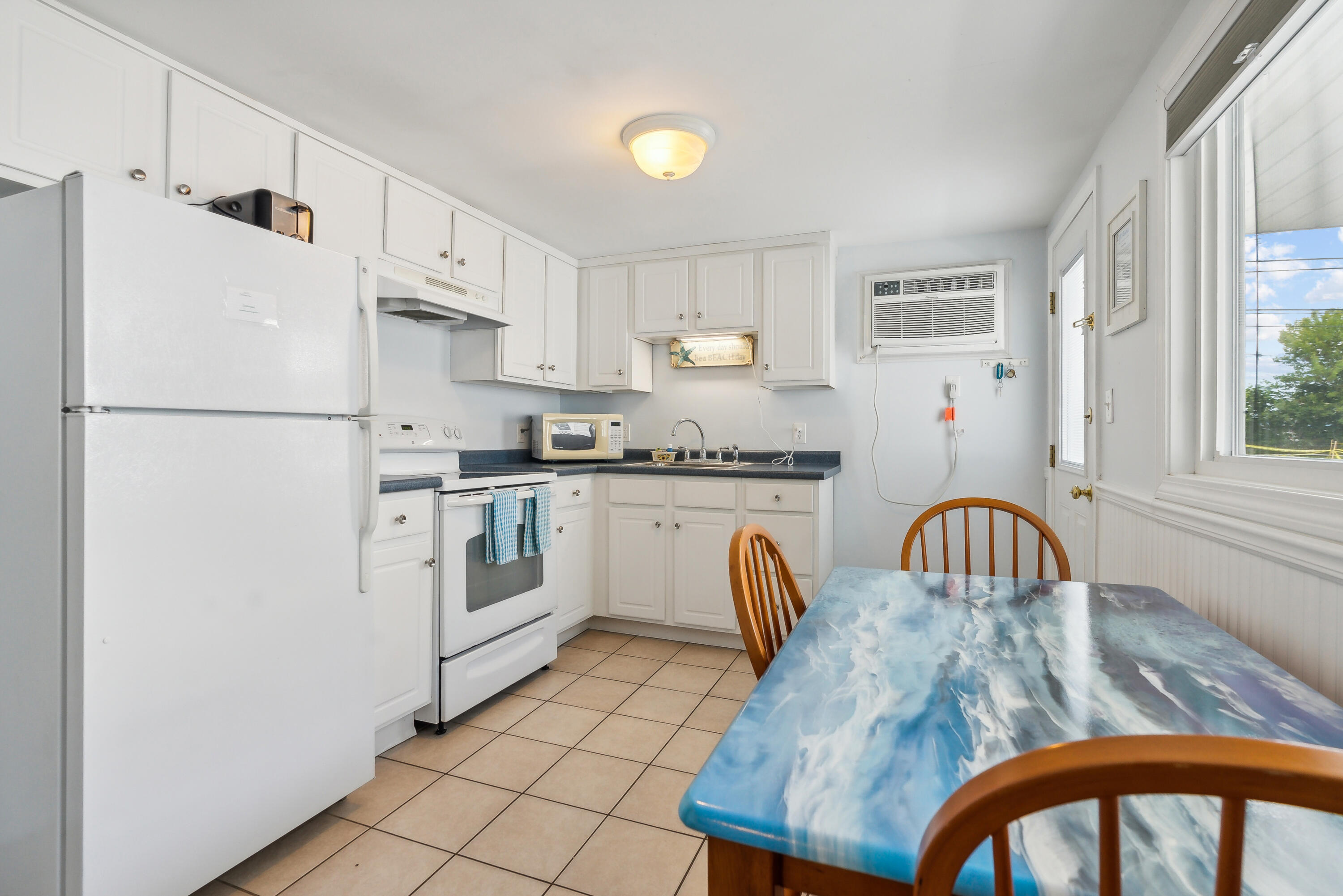 Kitchen with white cabinets, a breakfast table, and a window air conditioner.