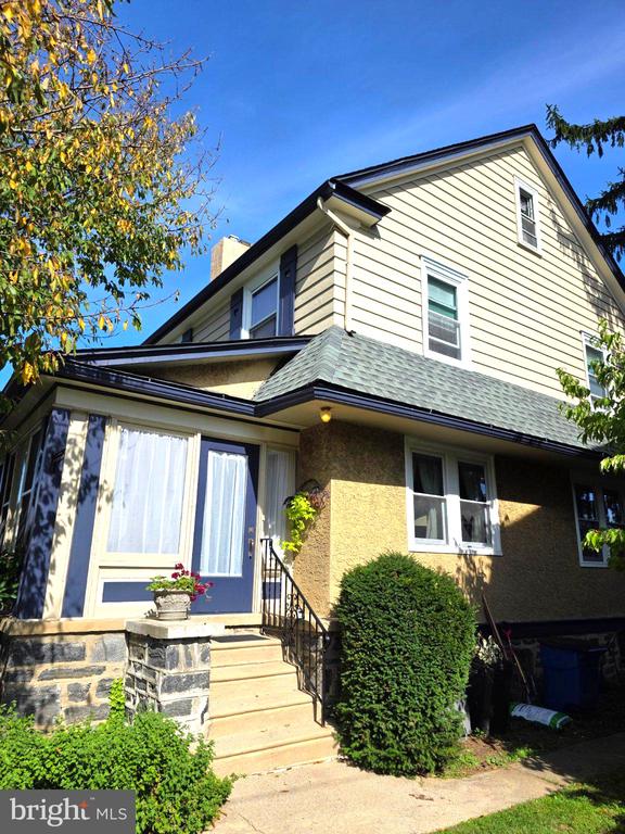 Two-story home with a blue entrance door, stone steps, and a landscaped front yard.