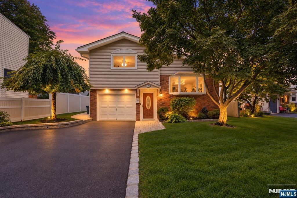 Two-story suburban house with brick accents and a single-car garage, photographed at dusk beneath a pink sky.