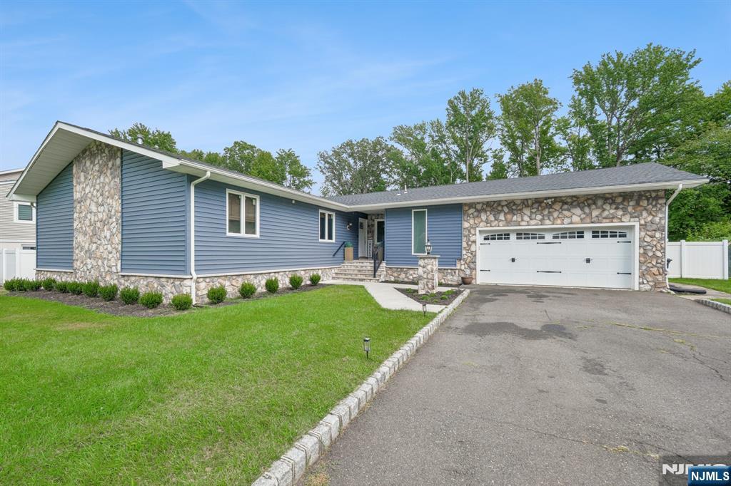 Blue single-story home with stone accents, a two-car garage, and a broad paved driveway.
