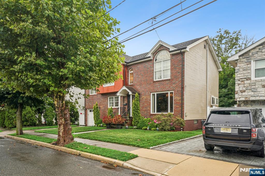 Two-story brick-and-siding house with an arched window, landscaped lawn, and driveway.