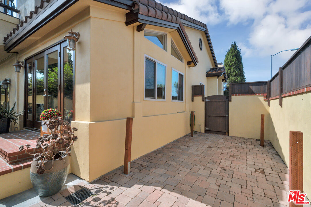 Paved side courtyard with a wooden gate beside a tan stucco home.