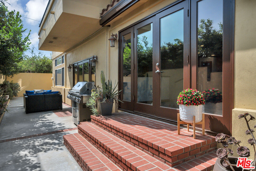 Exterior patio with brick steps, sliding glass doors, barbecue grill, and outdoor seating.