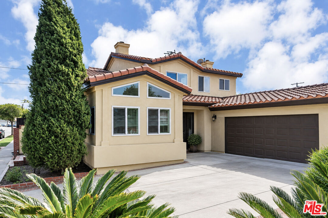 Two-story stucco home with a red tile roof, attached double garage, and broad driveway.