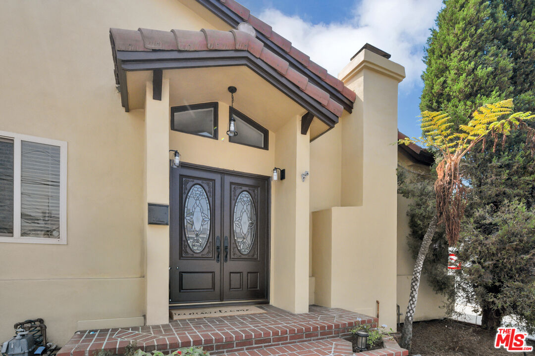 Home entrance with decorative-glass double doors, brick steps, and a tiled roof.