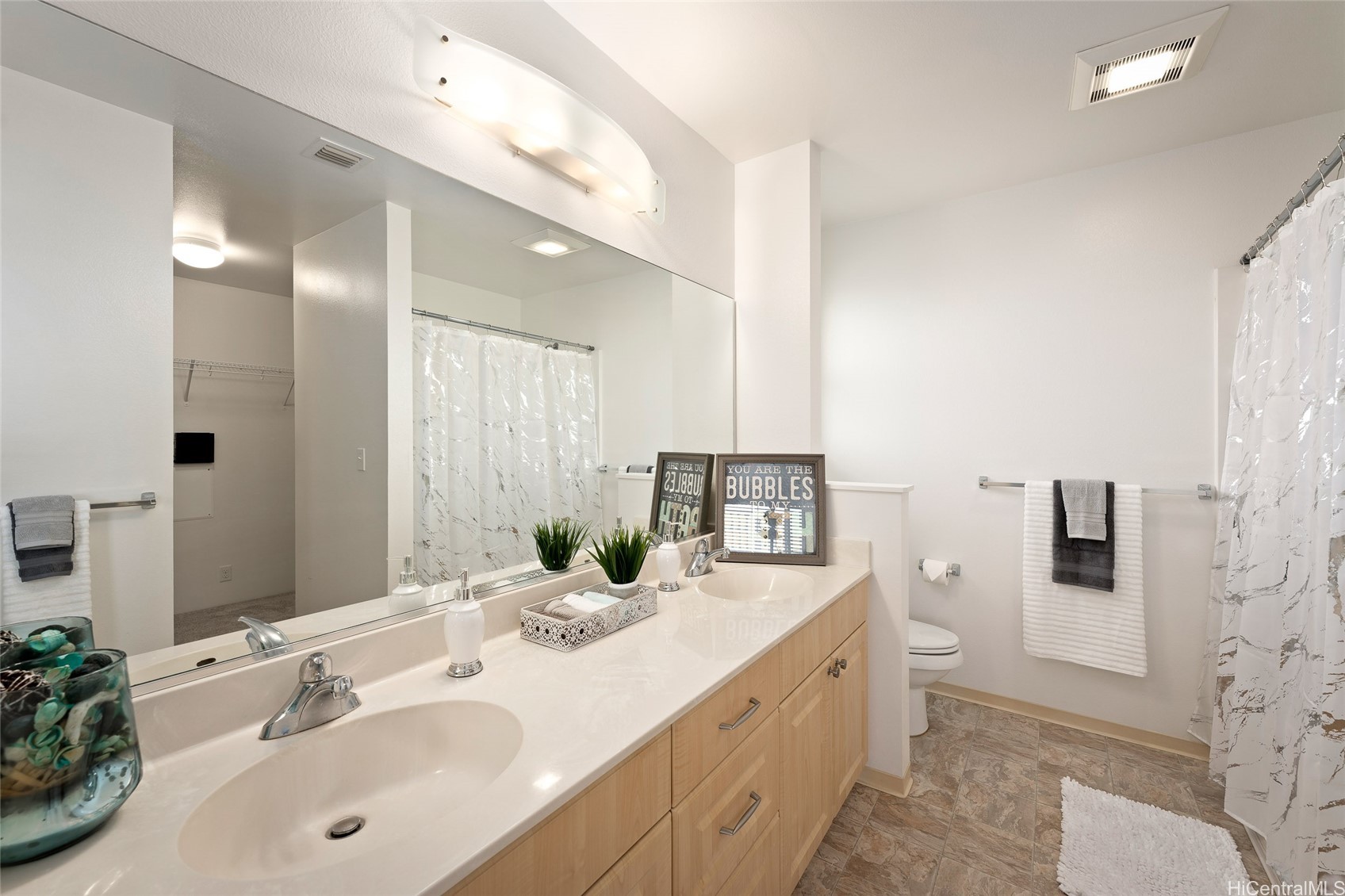 Bathroom with a double vanity, large mirror, and marble-pattern shower curtain.