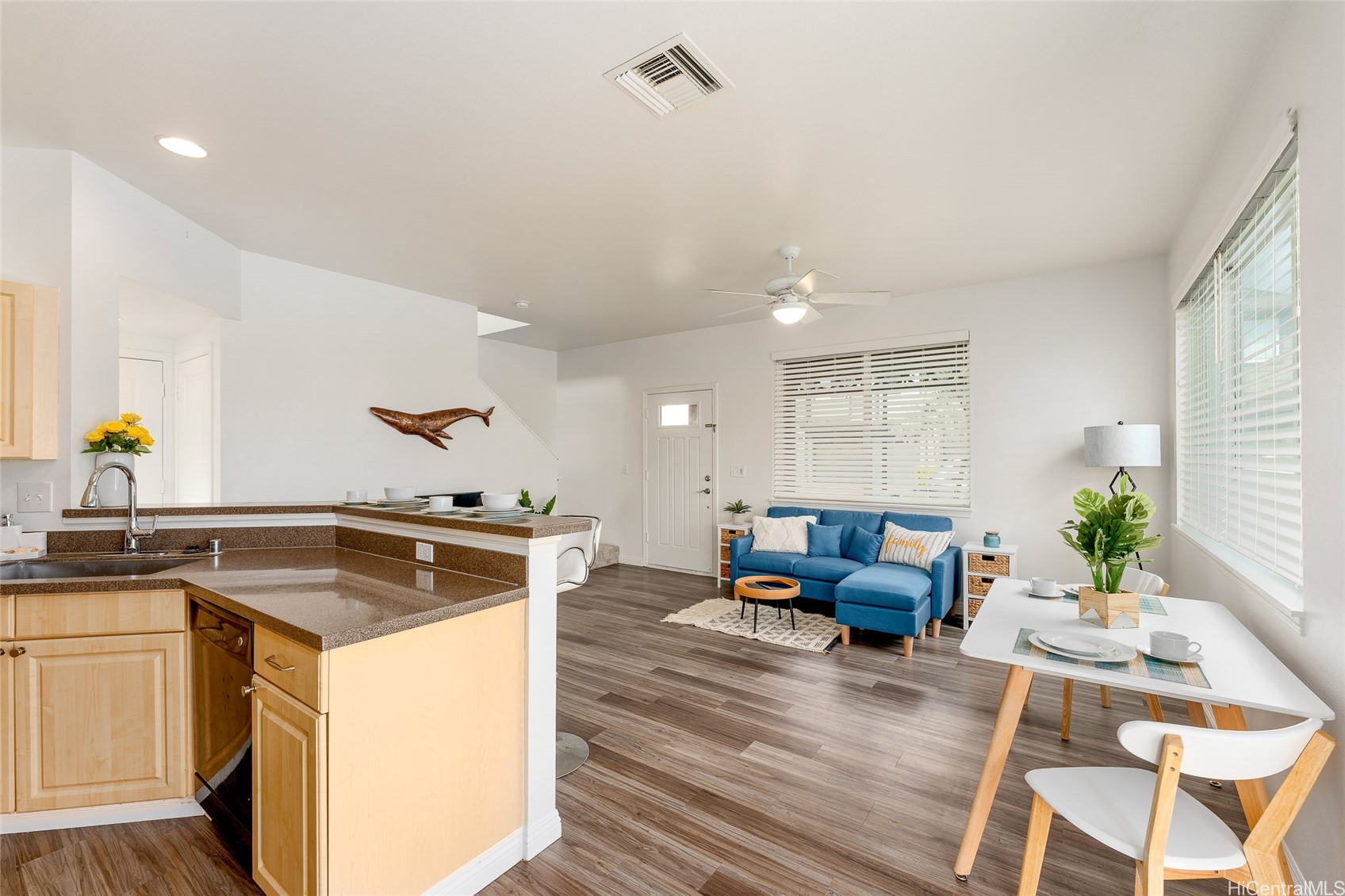 Open-plan kitchen and living room with a brown peninsula countertop and blue sectional sofa.