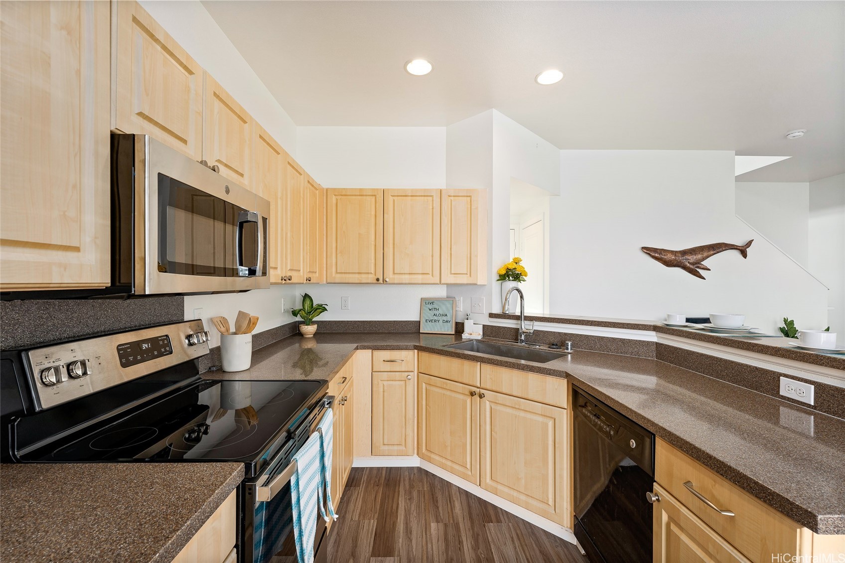 Kitchen with light wood cabinets, brown countertops, stainless steel appliances, and a whale wall decoration.