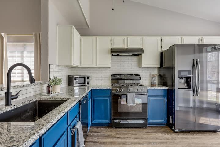 Kitchen with blue lower cabinets, granite counters, and stainless steel appliances.
