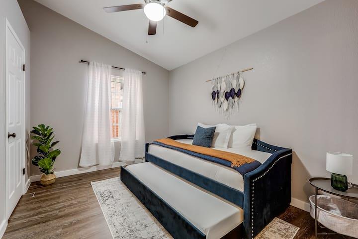 Bedroom with a dark blue daybed and pull-out trundle beneath a ceiling fan.